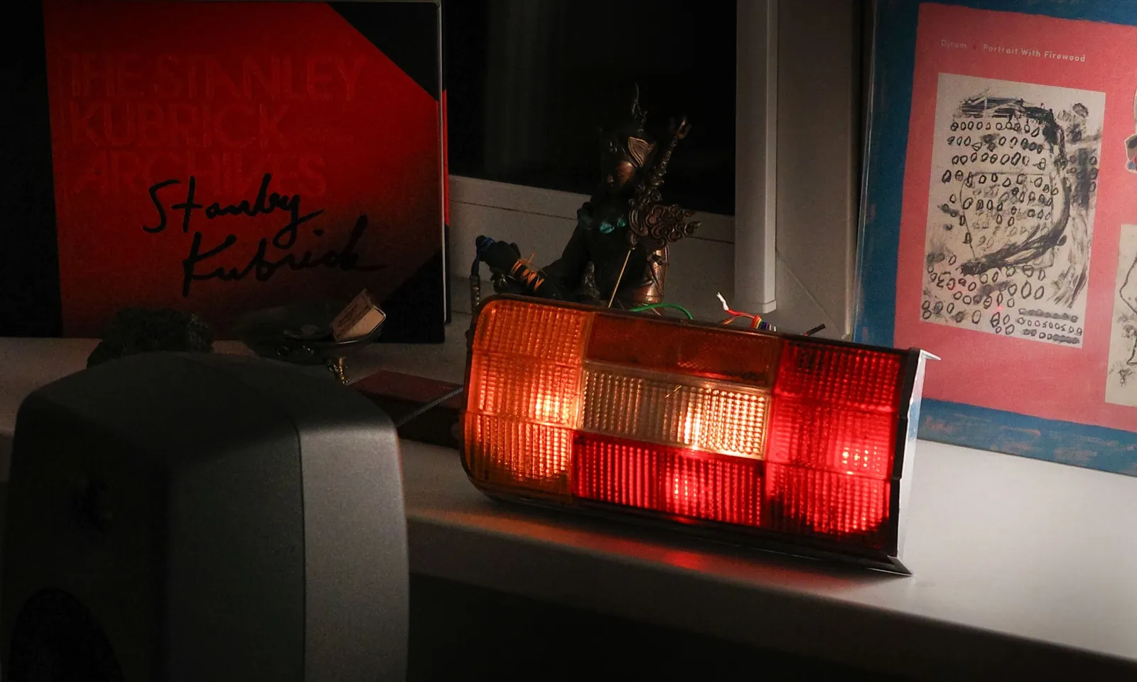 The SmartLada tail light lit on a windowsill at night: amber, white and red sections